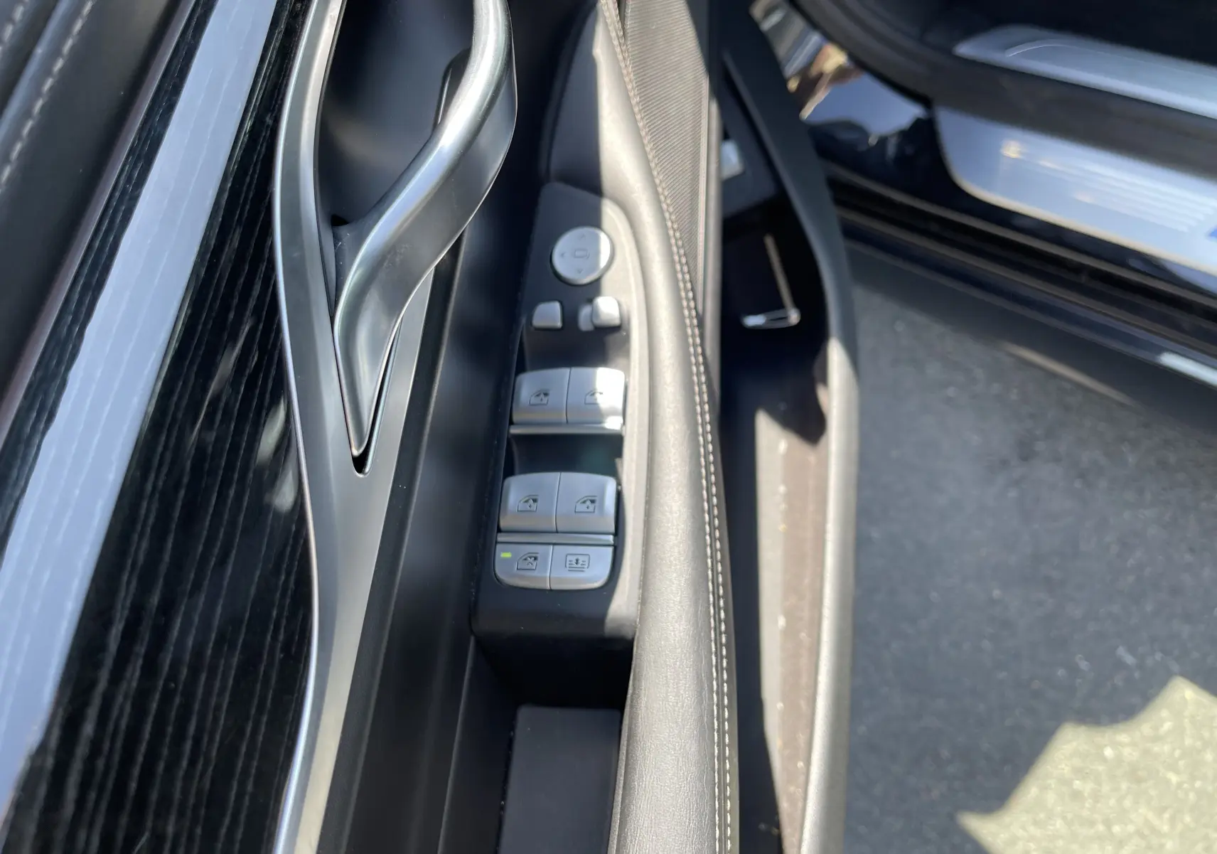 Gros plan sur la commande des vitres côté gauche en cuir noir de la BMW Série 7 G11 M Sport 2015.