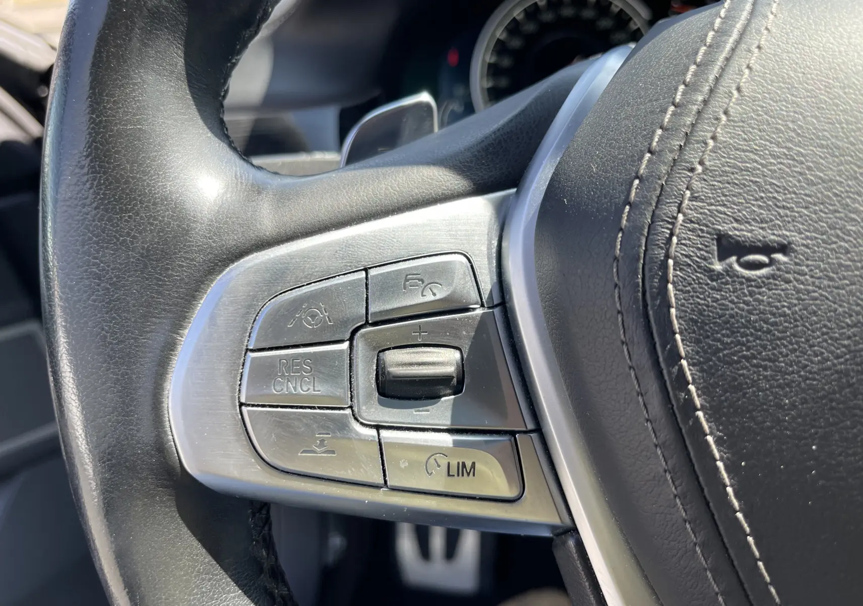 Gros plan sur les commandes du volant cuir noir de la BMW Série 7 G11 M Sport 730 XDA diesel de 2015.