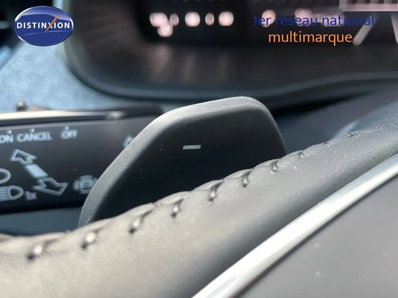 Gros plan sur la palette de changement de vitesse au volant du Skoda Kamiq gris argent, avec commandes au tableau de bord floues.