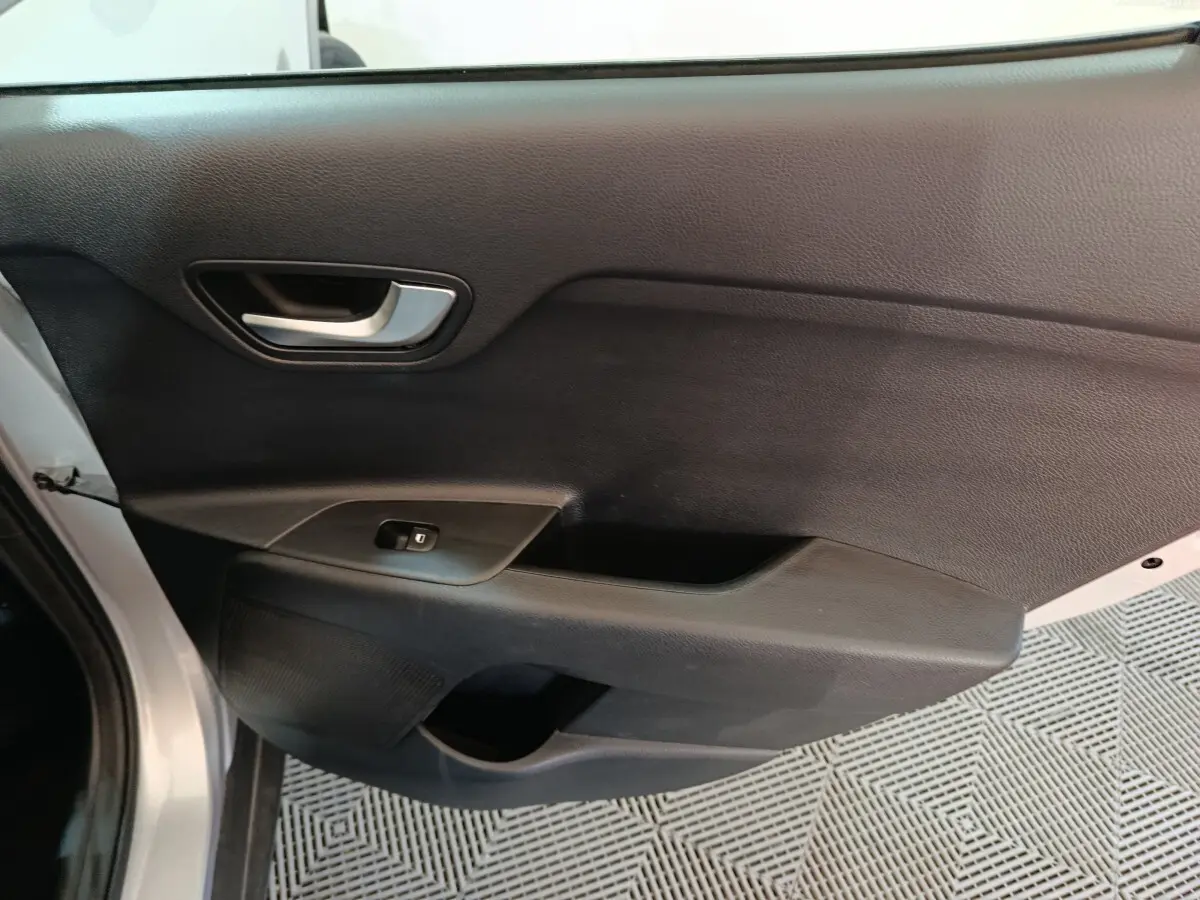 Vue intérieure du panneau de porte avant gauche gris clair du KIA STONIC 2022 avec poignée argentée et commande de vitre.