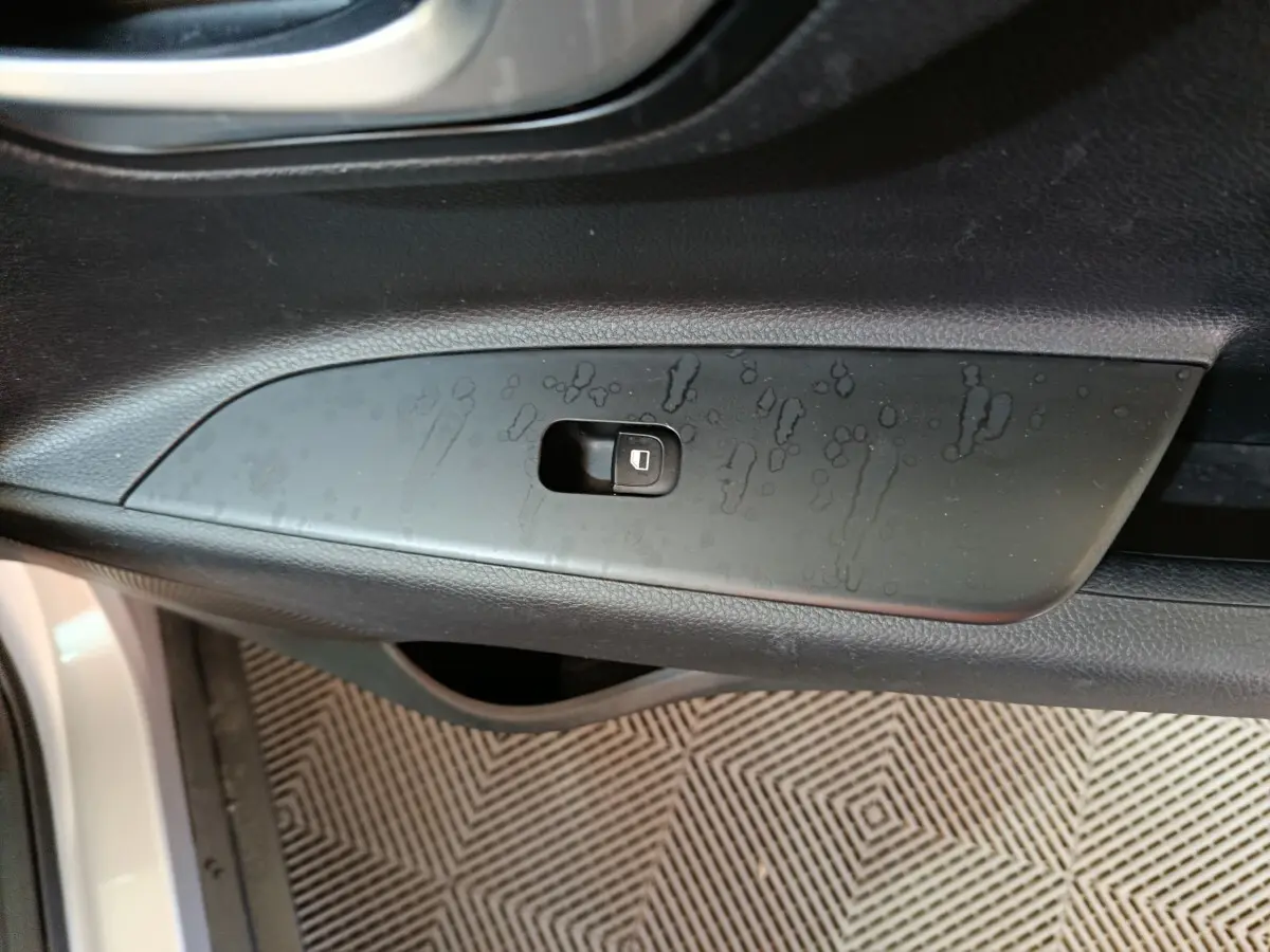 Gros plan sur le bouton de verrouillage des portes côté conducteur d’un KIA Stonic gris clair, intérieur noir.