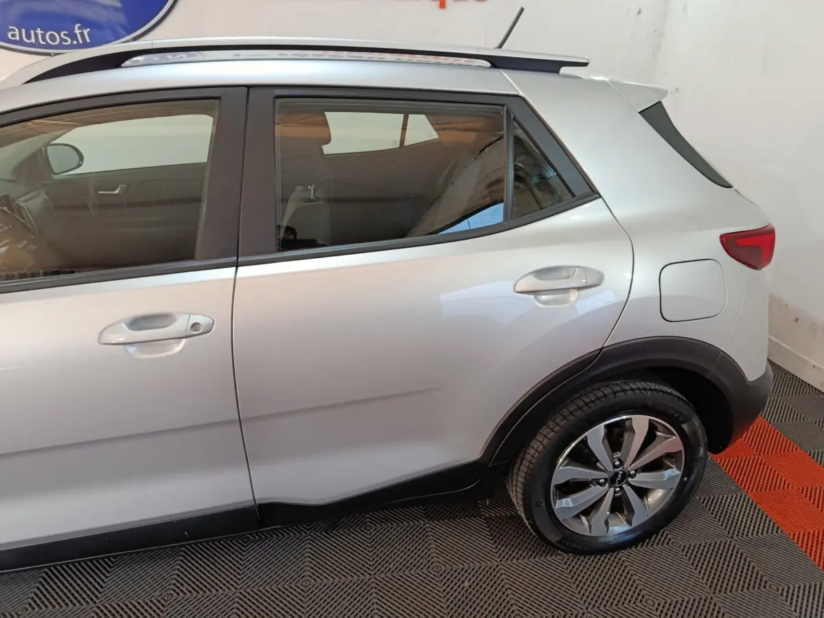 Vue latérale droite d'un KIA Stonic gris clair 2022, mettant en valeur les jantes alliage et les contours noirs des passages de roues.