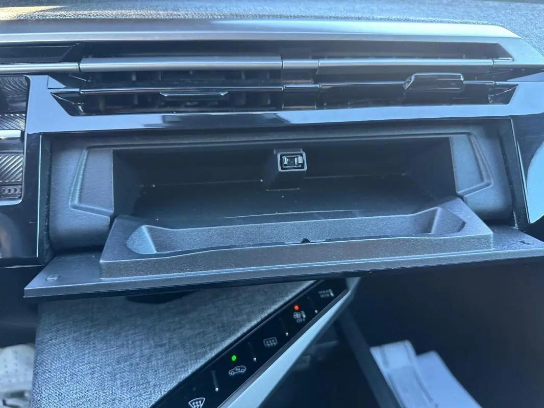 Gros plan sur la boîte à gants ouverte du Peugeot 3008 Hybrid blanc, montrant une prise USB intégrée.