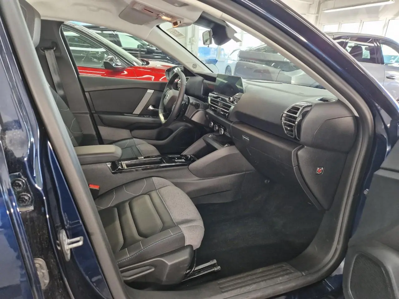 Intérieur avant droit d'une Citroën C4 2024 bleu Eclipse, avec sièges gris et noir et tableau de bord moderne.