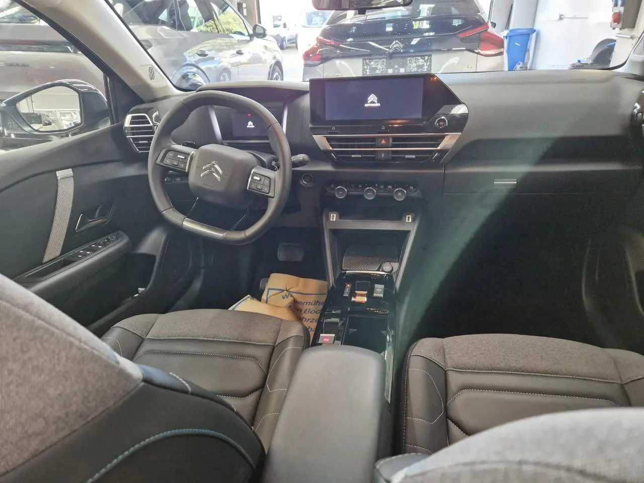 Vue intérieure avant de la Citroën C4 2024, tableau de bord noir avec écran tactile central 10 pouces et sièges gris.