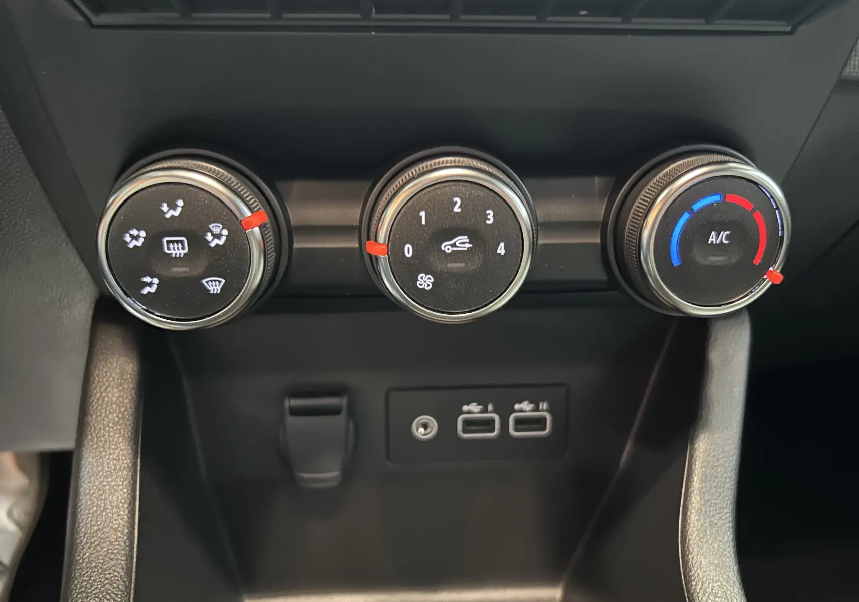 Gros plan sur les commandes de climatisation manuelle et les ports USB du tableau de bord d'une Renault Clio V gris schiste.