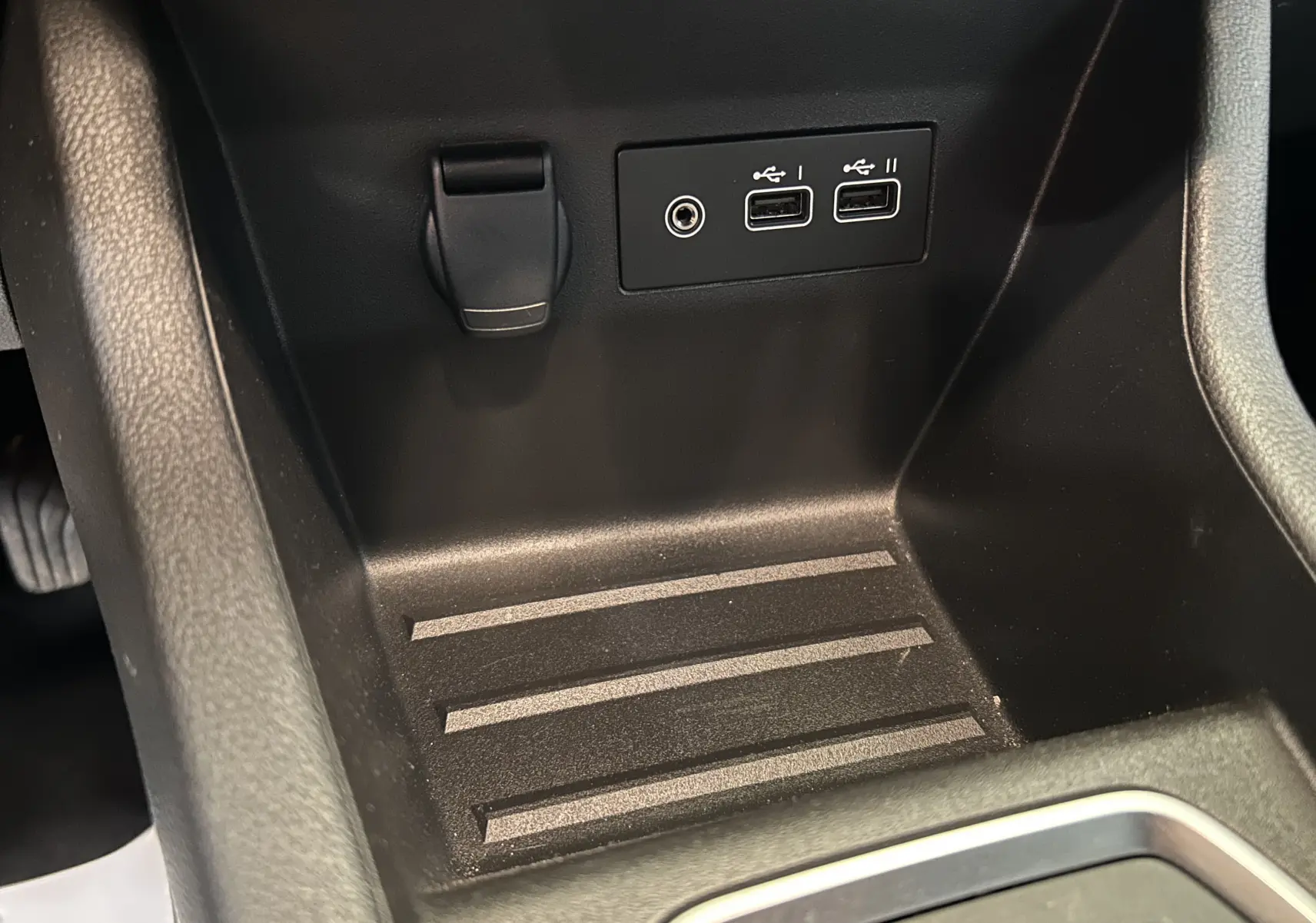 Gros plan sur la console centrale noire de la Renault Clio V, montrant deux ports USB et une prise jack.