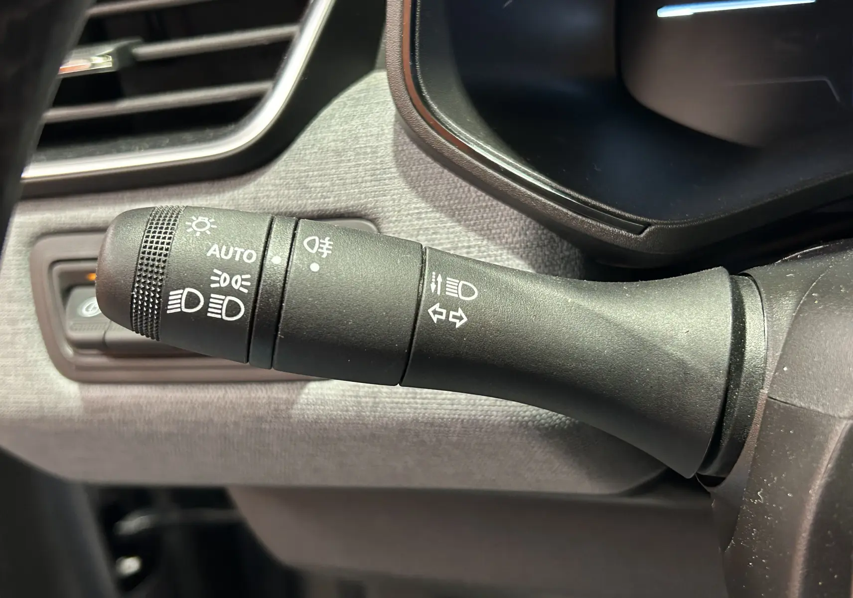 Gros plan sur la manette de commande des phares et clignotants dans l’habitacle gris d’une Renault Clio V TCe 90ch.