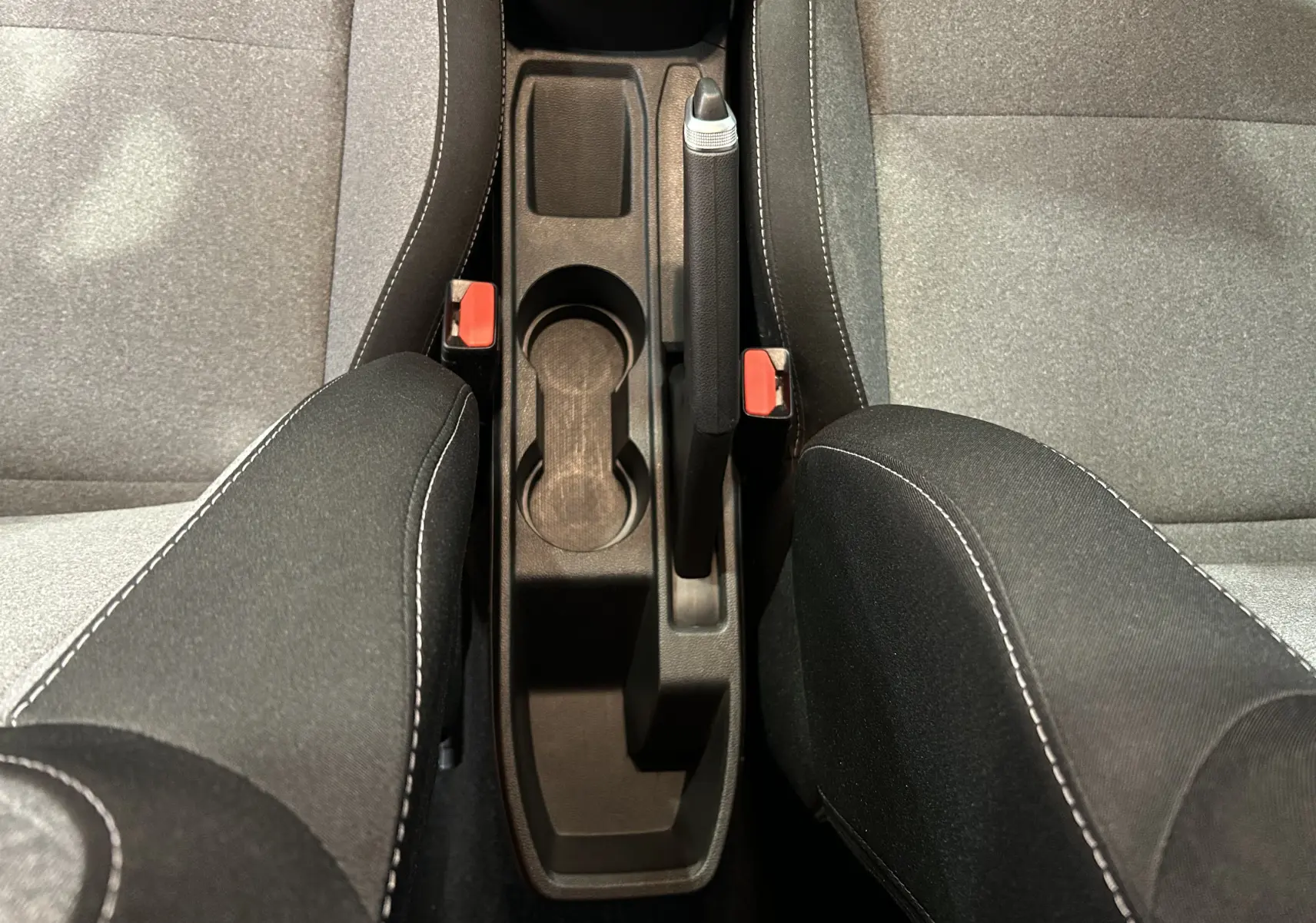 Vue plongeante sur la console centrale noire avec frein à main et sièges tissu gris et noir de la Renault Clio V.