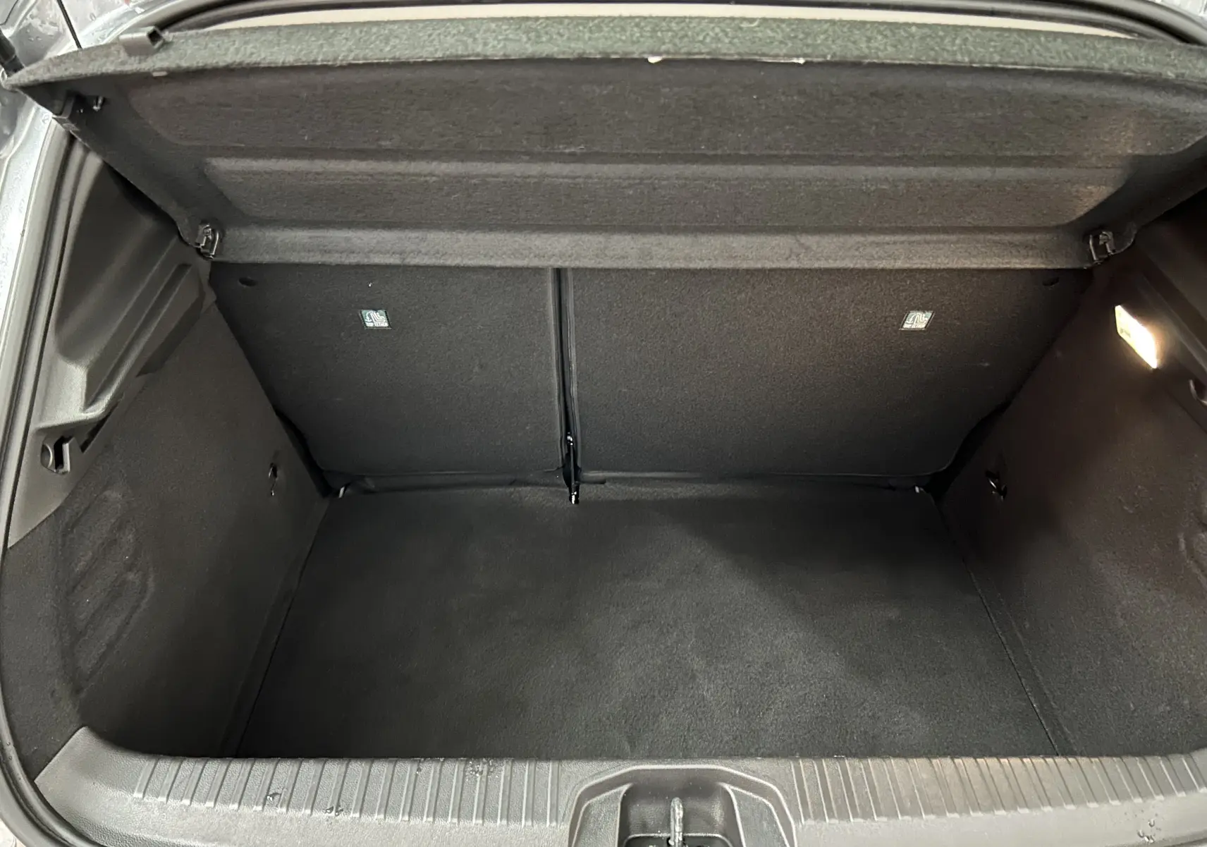 Coffre ouvert en vue plongeante d'une Renault Clio V gris schiste, montrant un espace de chargement propre et vide.