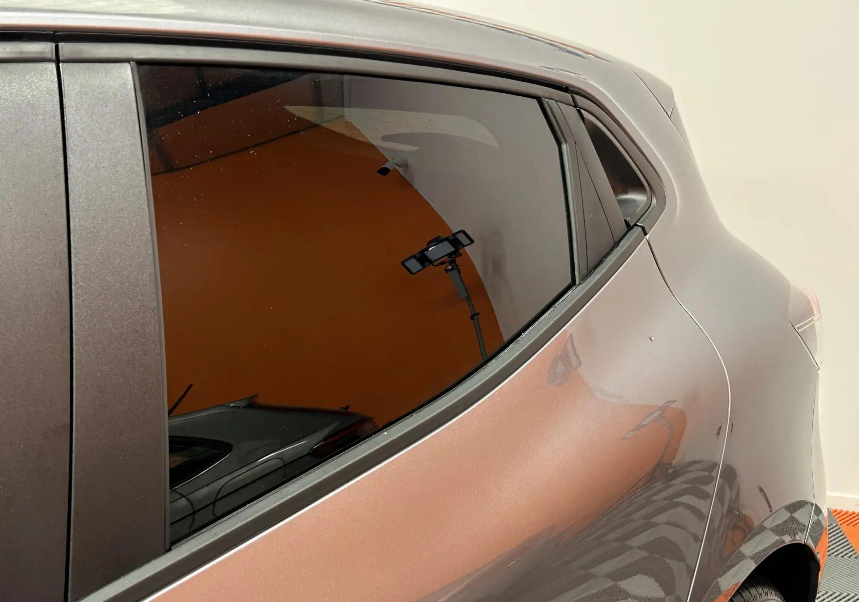 Vue rapprochée du côté arrière gauche de la Renault Clio V gris schiste métal, mettant en valeur la courbe de la carrosserie et la vitre teintée.