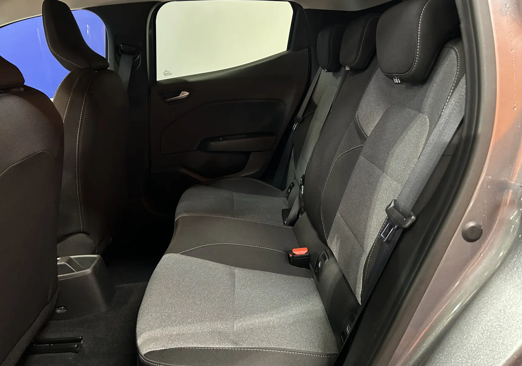 Vue intérieure côté droit des sièges arrière en tissu gris et noir de la Renault Clio V 2025, porte ouverte.