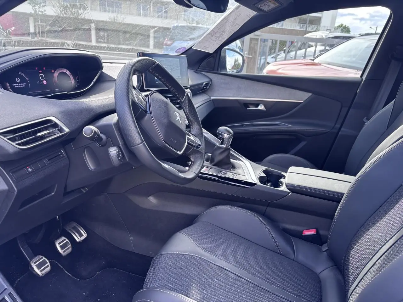 Intérieur du Peugeot 5008 2022 blanc, vue côté conducteur, volant compact, boîte manuelle et sièges en cuir noir.