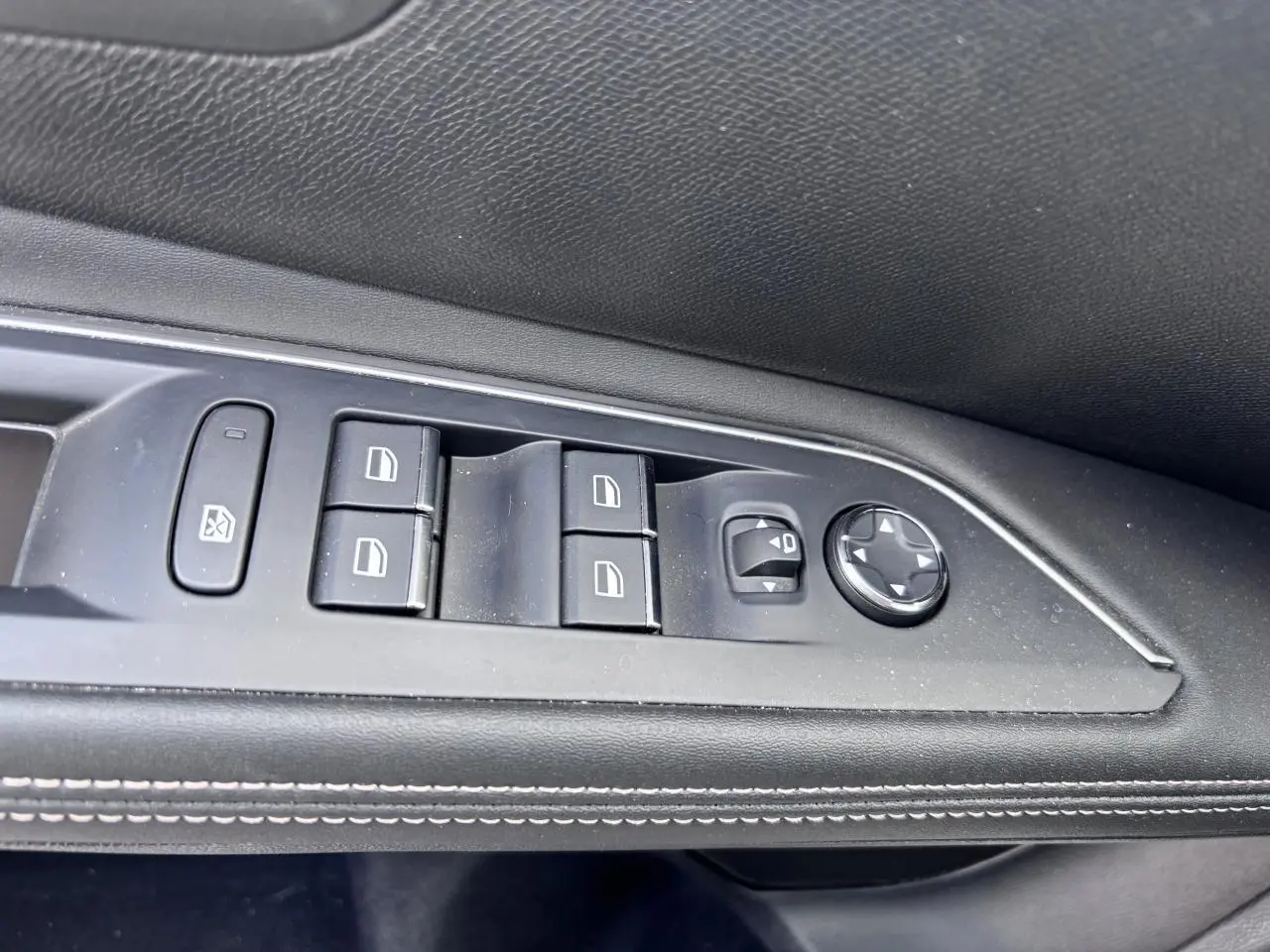 Gros plan sur les commandes de lève-vitres et réglage des rétroviseurs côté conducteur d’un Peugeot 5008 blanc.