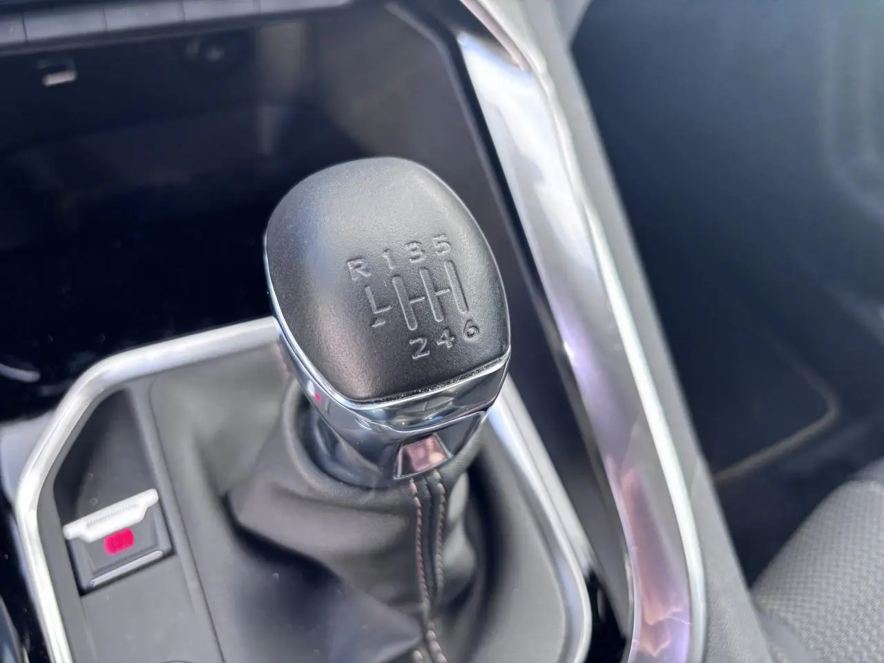 Le levier de vitesse manuel noir du Peugeot 5008 blanc, avec indication des six rapports et de la marche arrière.