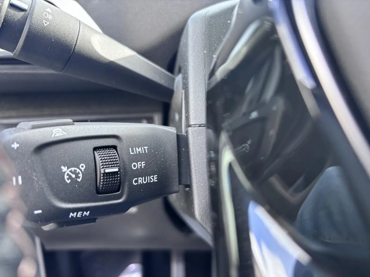 Gros plan sur la commande de régulateur de vitesse du Peugeot 5008 blanc, vue côté gauche du volant.