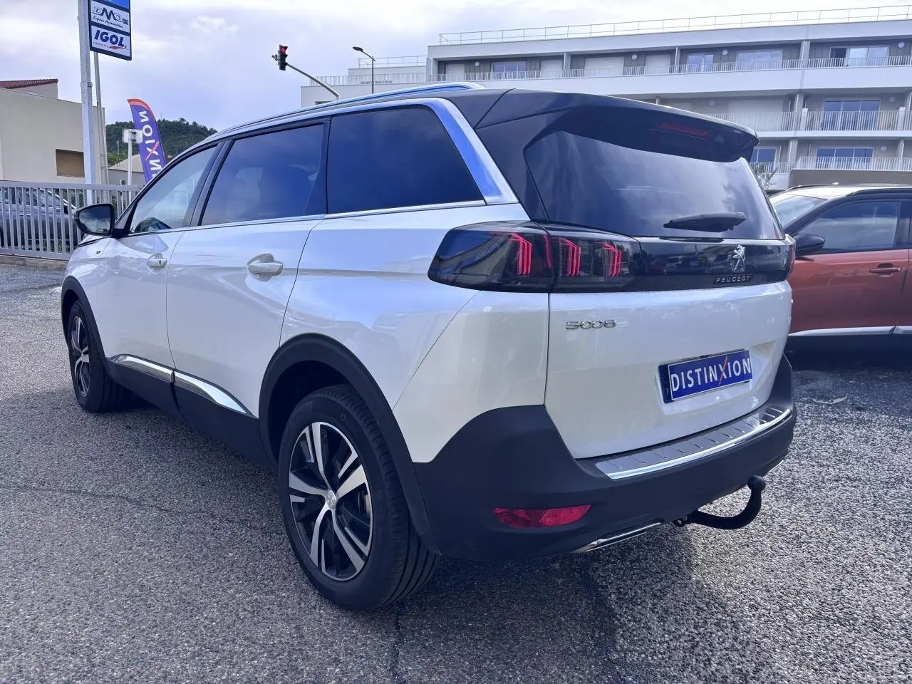 Vue 3/4 arrière droite d'un Peugeot 5008 blanc 2022 avec feux arrière LED et attelage visible.