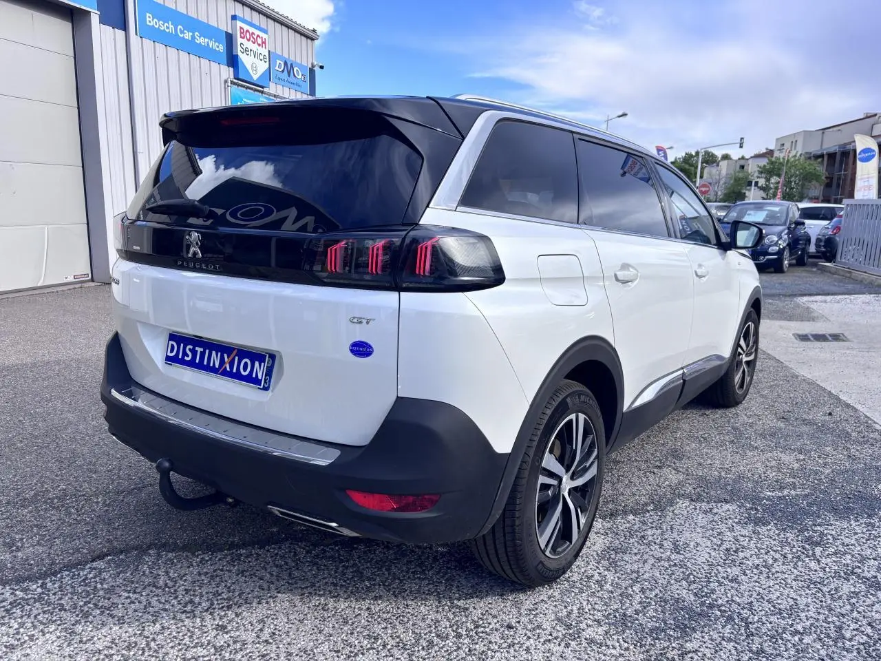 Vue 3/4 arrière droite d'un Peugeot 5008 blanc 2022 avec toit noir et feux arrière à griffes rouges distinctifs.