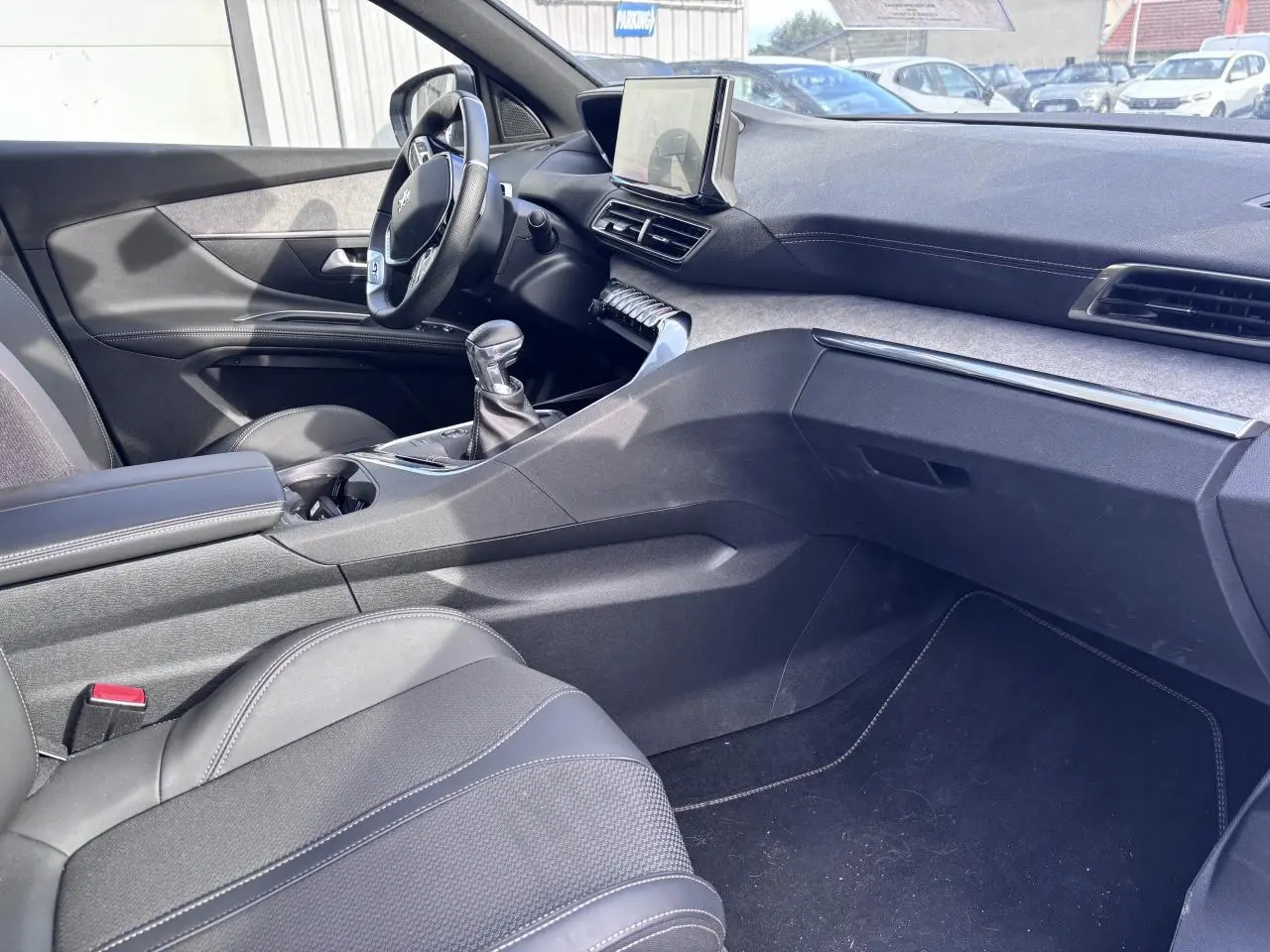 Vue intérieure côté conducteur du Peugeot 5008 blanc 2022, mettant en valeur la console centrale et le levier de vitesse manuel.