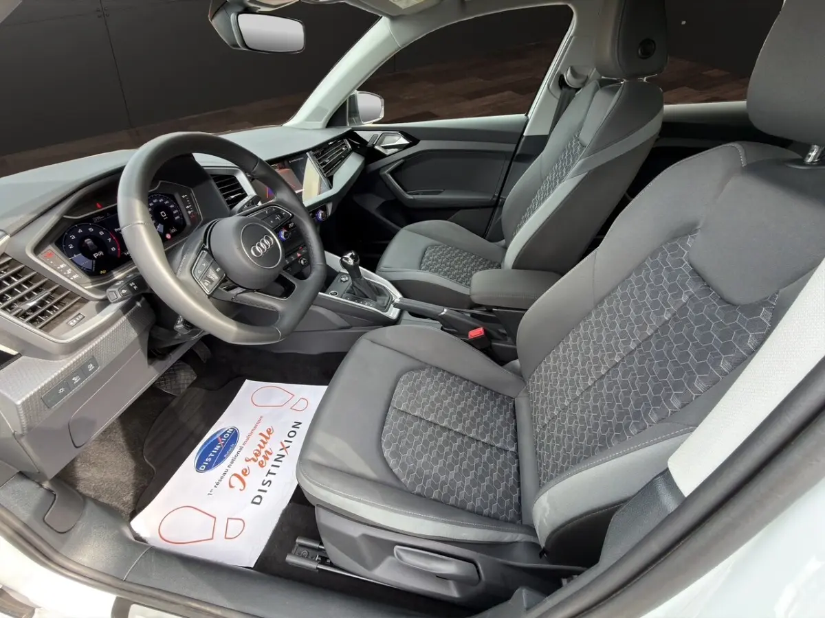 Vue intérieure côté conducteur de l'Audi A1 Sportback 2025, sièges gris et volant multifonction cuir.