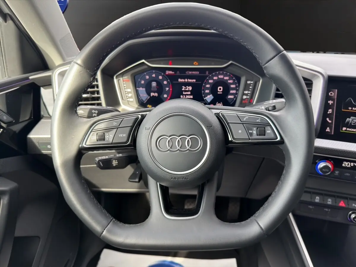 Vue rapprochée du volant cuir multifonction noir de l'Audi A1 Sportback 2025 avec tableau de bord numérique.