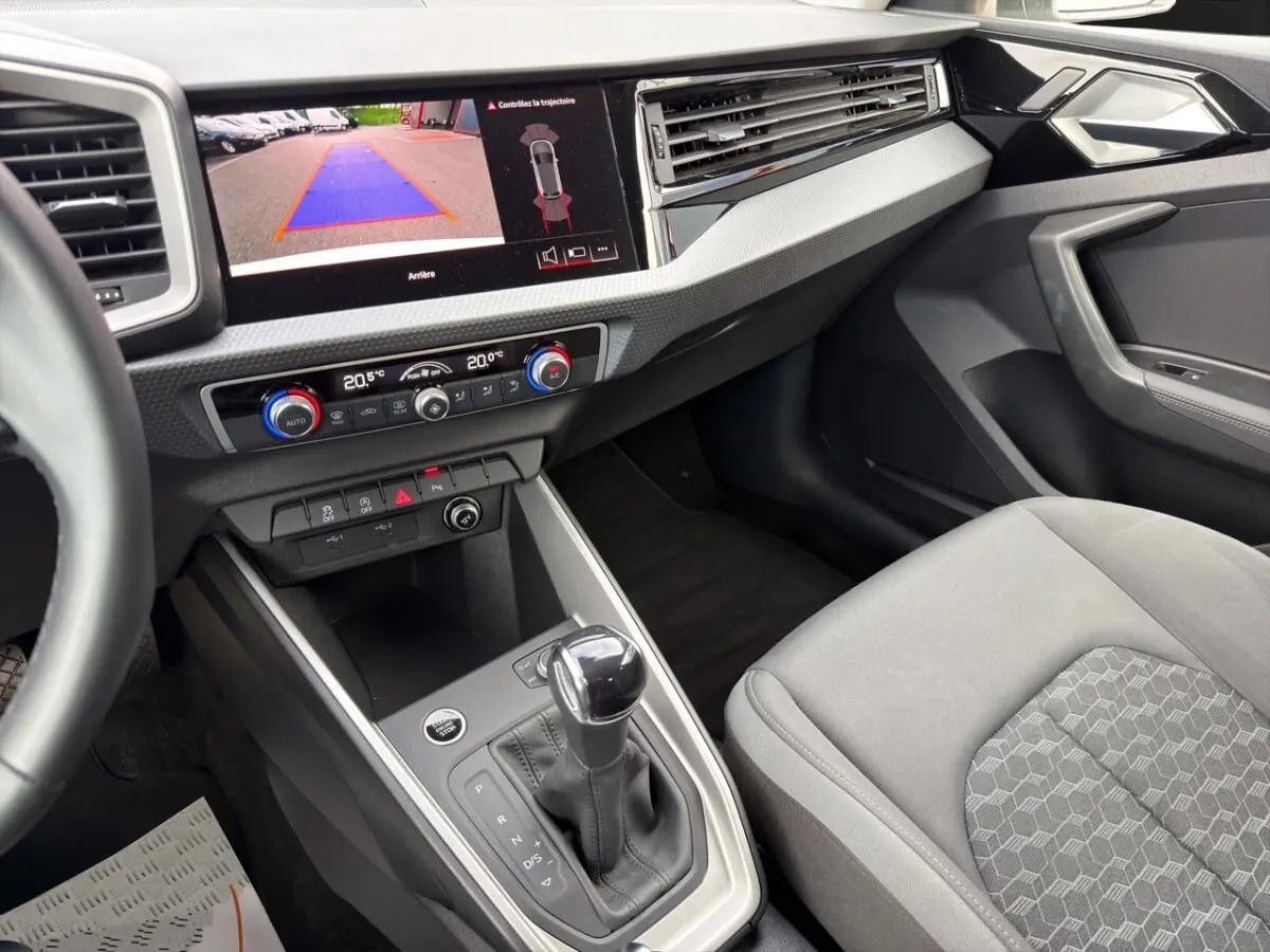 Vue intérieure côté passager de l'Audi A1 Sportback 2025 avec écran caméra de recul et levier de boîte automatique.