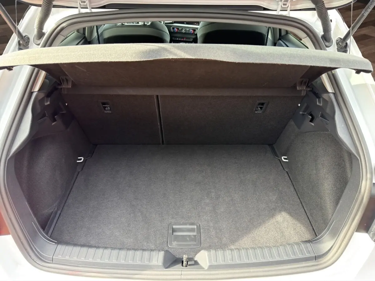 Coffre ouvert vu de l'arrière d'une Audi A1 Sportback blanche, montrant l'espace de chargement vide et la plage arrière.