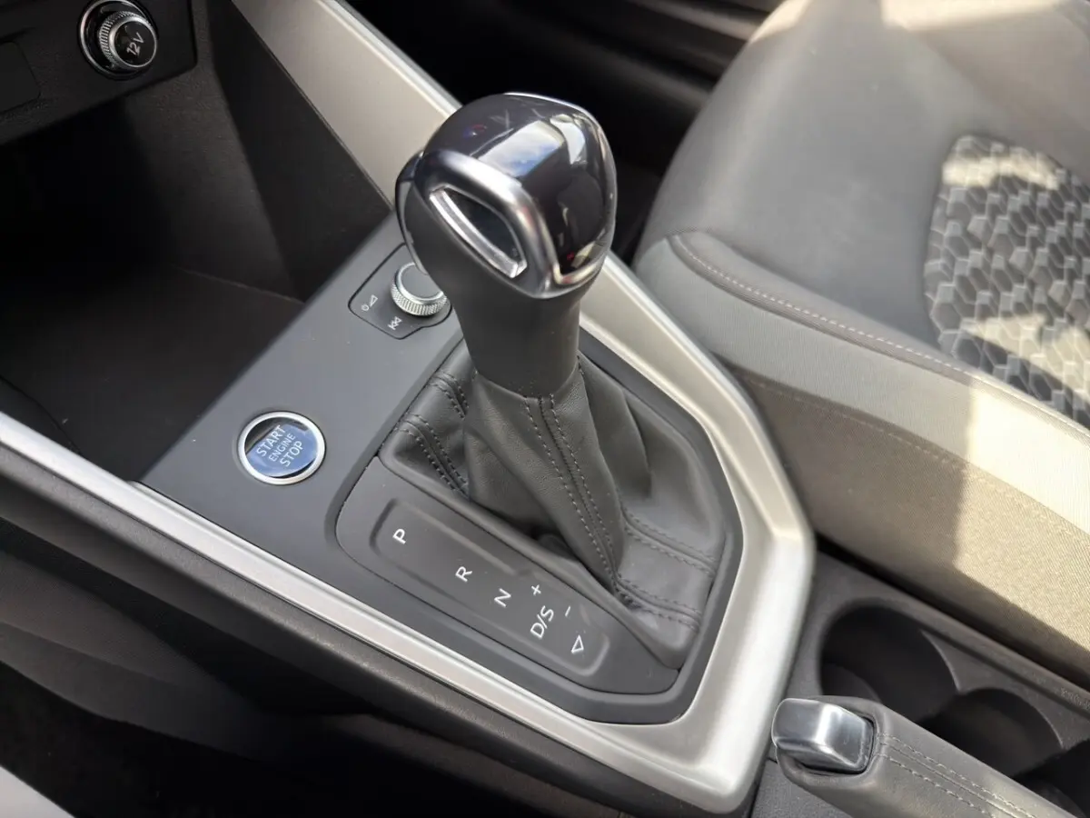 Gros plan sur la console centrale de l'Audi A1 Sportback blanche, mettant en valeur le levier de vitesse automatique et le bouton Start/Stop.