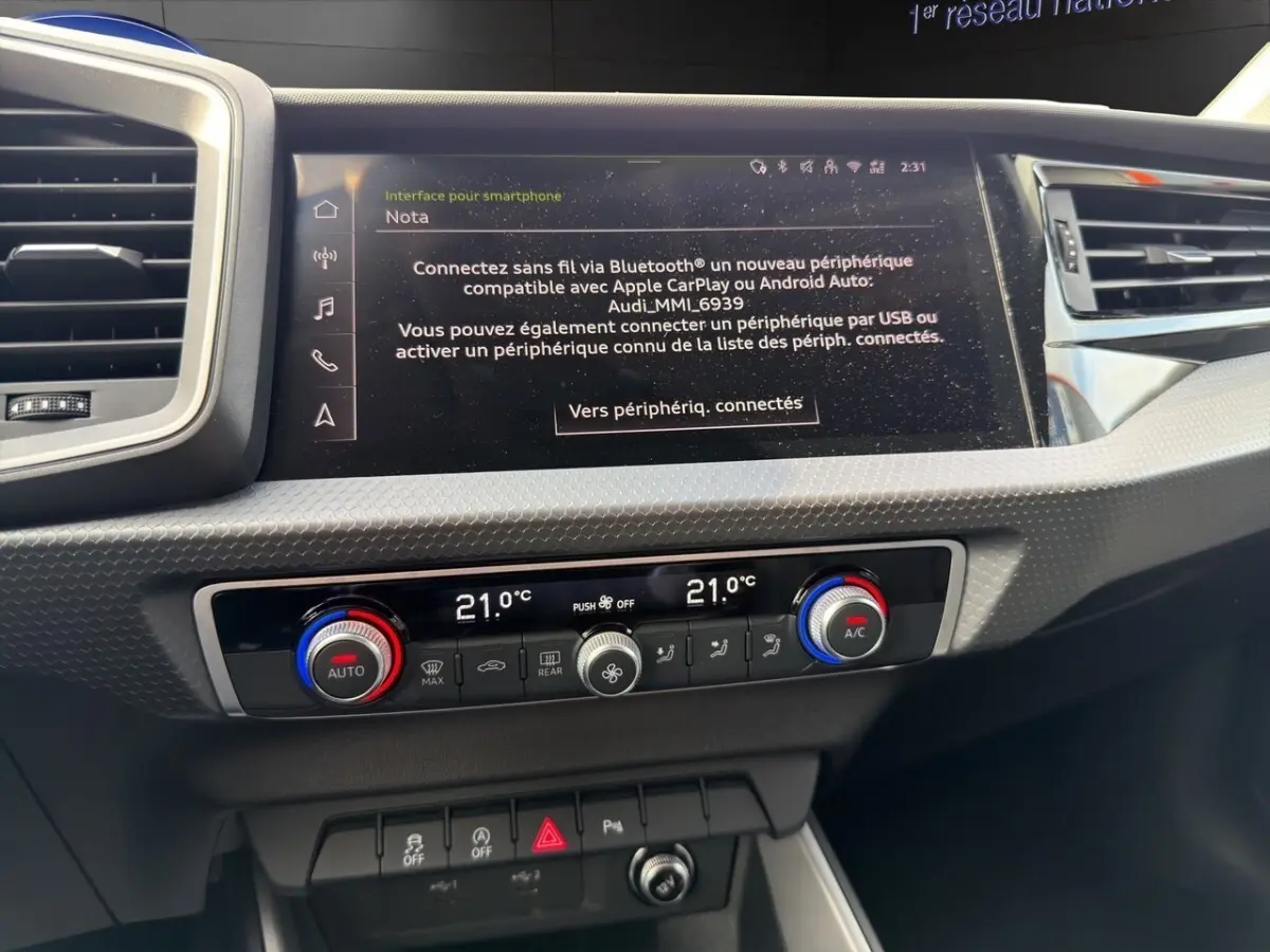 Vue rapprochée du tableau de bord de l'Audi A1 Sportback 2025, montrant l'écran tactile et les commandes de climatisation.