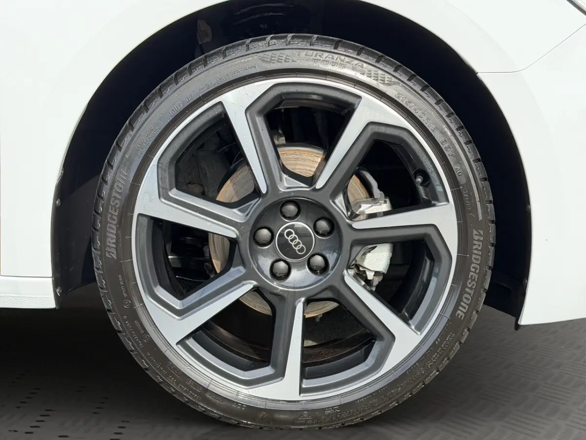 Gros plan sur la roue avant droite d'une Audi A1 Sportback blanche, jante alliage gris foncé à design moderne.