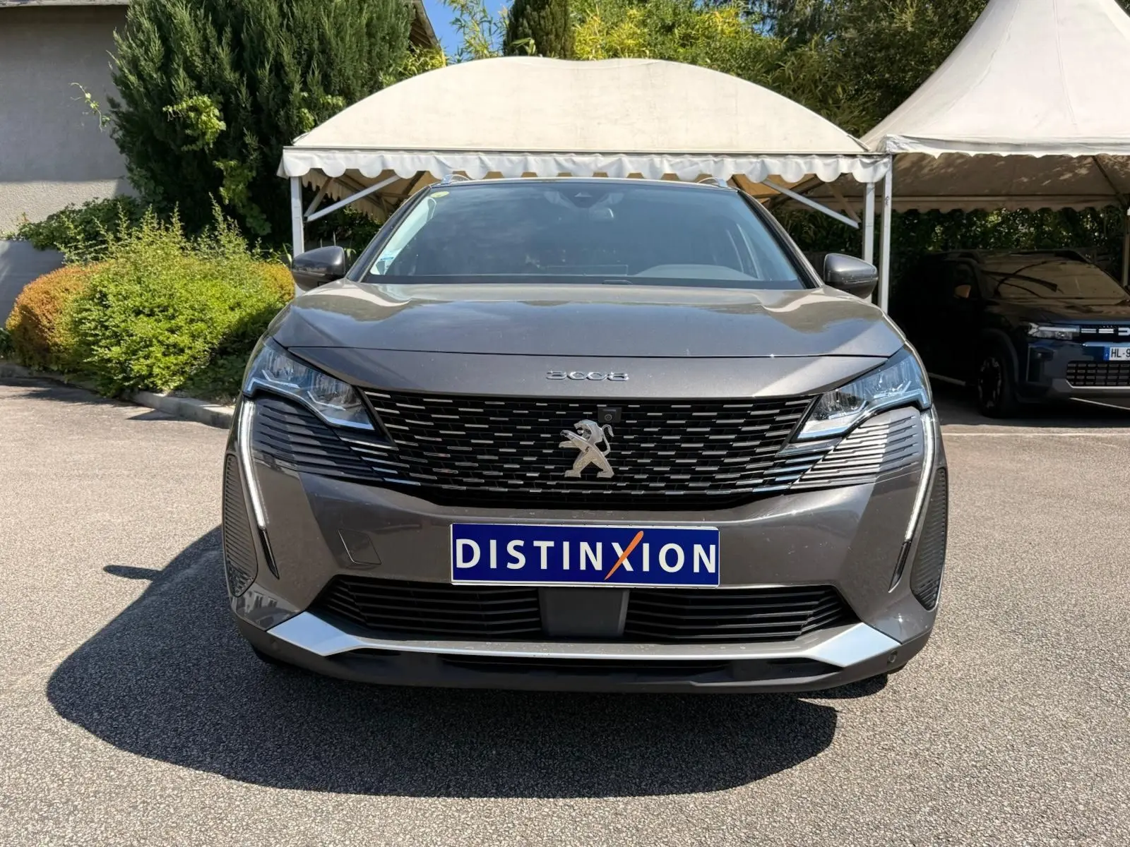 Vue frontale d’un Peugeot 3008 gris platinium 2021 avec calandre noire et logo lion central bien visible.