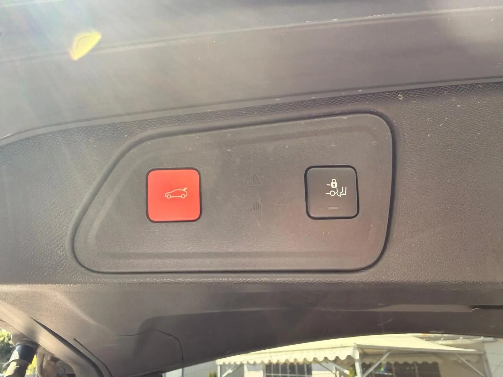 Gros plan sur les boutons d'ouverture et de verrouillage du hayon du Peugeot 3008 gris platinium, intérieur du coffre.