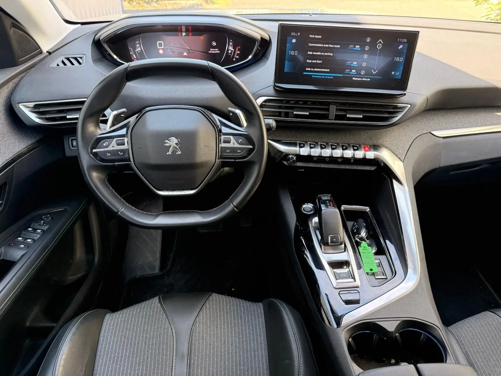 Vue intérieure du poste de conduite du Peugeot 3008 gris platinium, avec volant compact, écran tactile et console centrale moderne.
