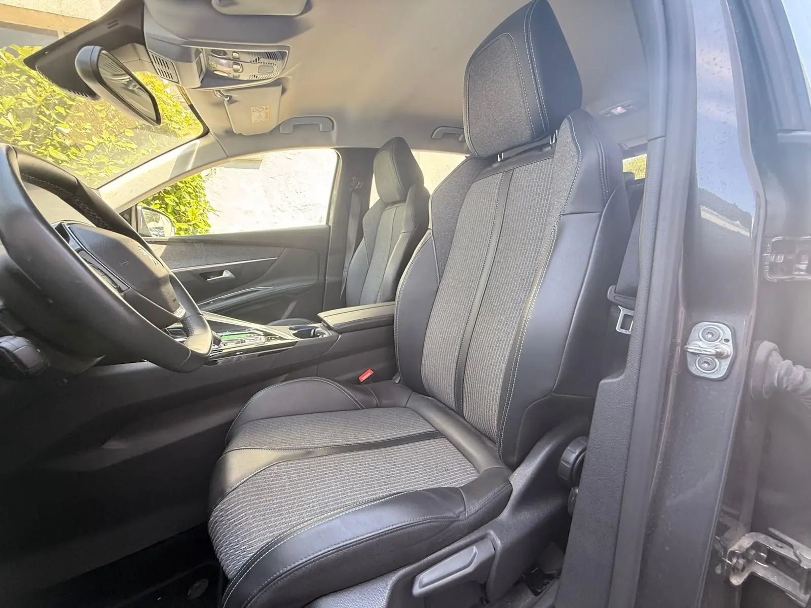 Vue intérieure côté conducteur du Peugeot 3008 2021, montrant les sièges en tissu et cuir noir avec surpiqûres contrastées.