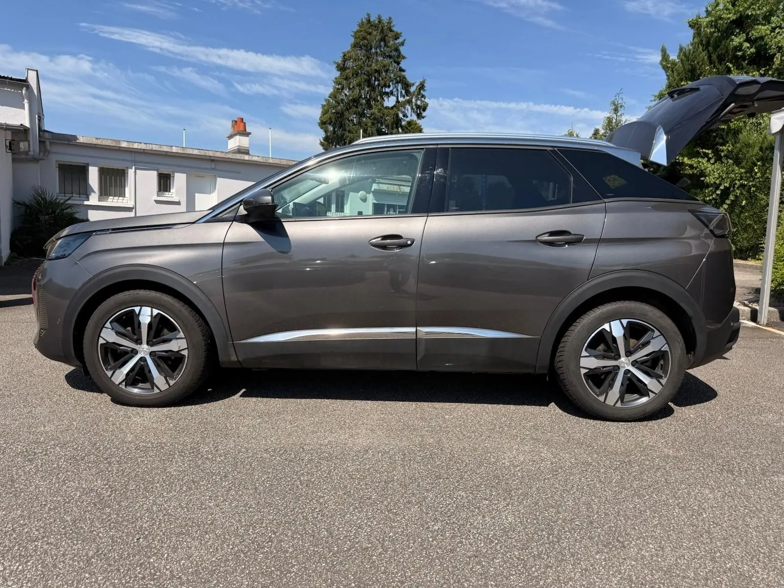 Peugeot 3008 gris platinium vue de profil côté gauche, hayon arrière ouvert et jantes bi-ton visibles.