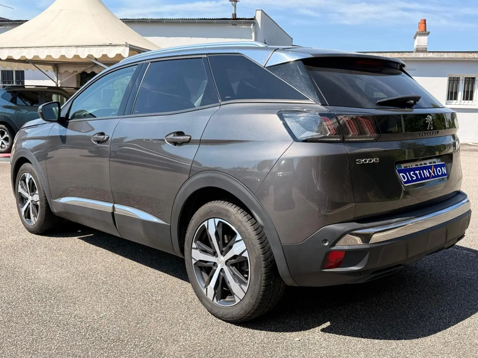 Peugeot 3008 gris platinium en 3/4 arrière droit, soulignant ses feux arrière distinctifs et jantes bi-ton.