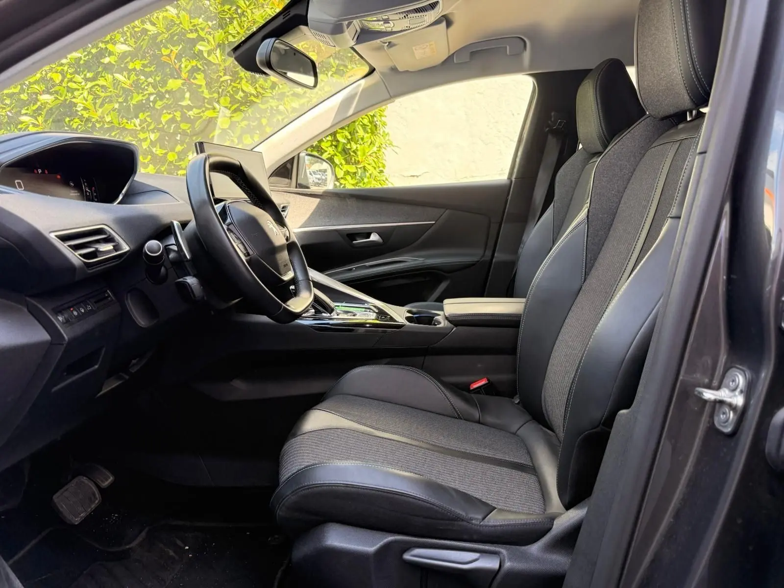 Vue intérieure côté conducteur du Peugeot 3008 gris platinium, mettant en valeur les sièges mixtes tissu et cuir et le tableau de bord moderne.