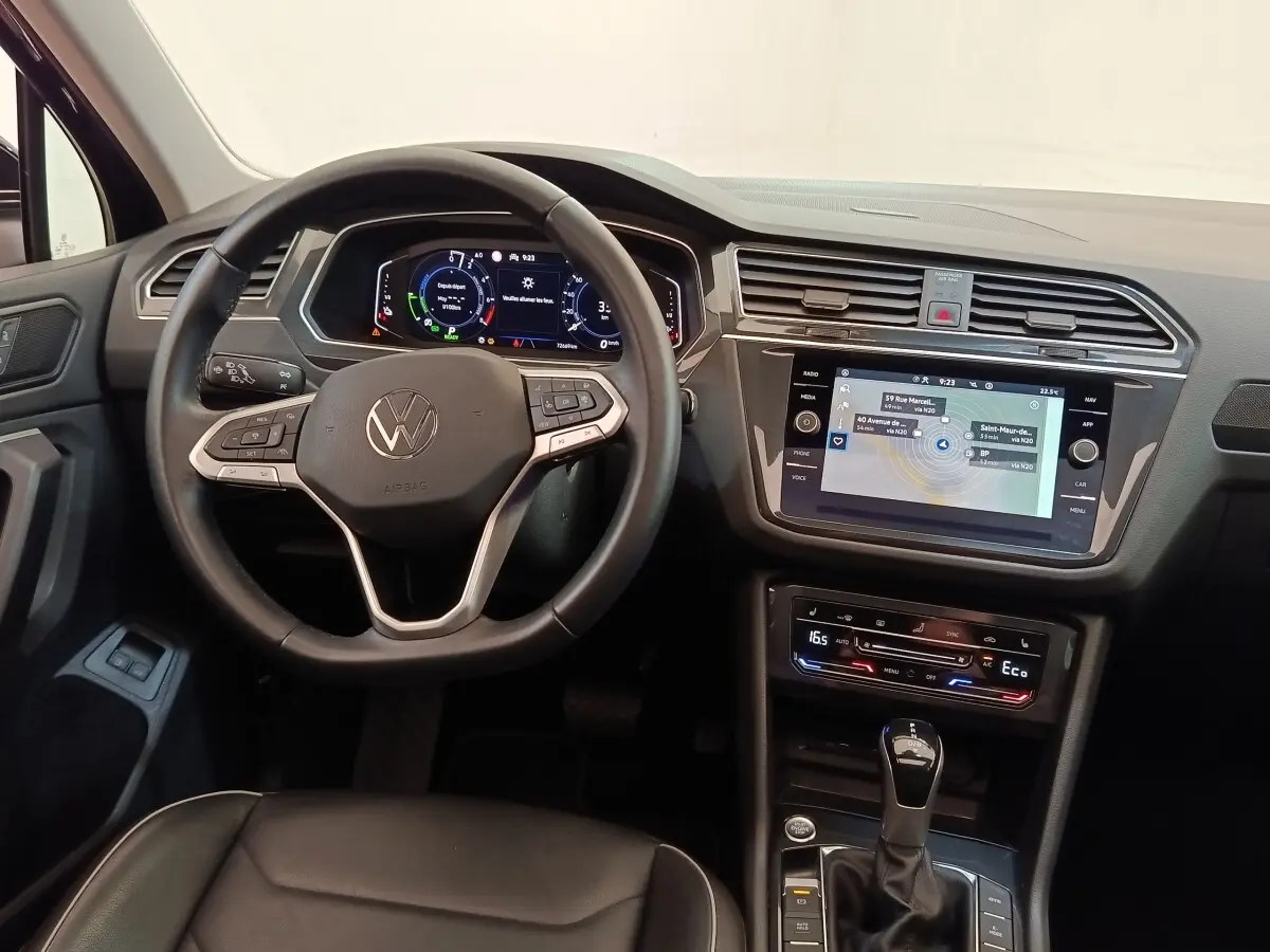 Vue intérieure du tableau de bord et volant noir du Volkswagen Tiguan 1.4 eHybrid 2022 avec écran tactile et affichage numérique.