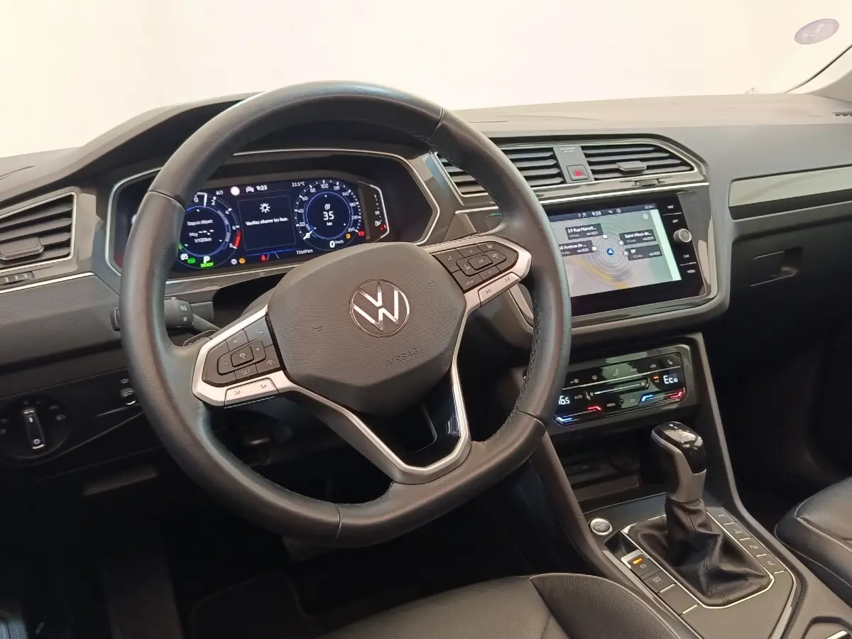 Vue intérieure du tableau de bord et volant noir du Volkswagen Tiguan 1.4 eHybrid 2022 avec écran tactile central.
