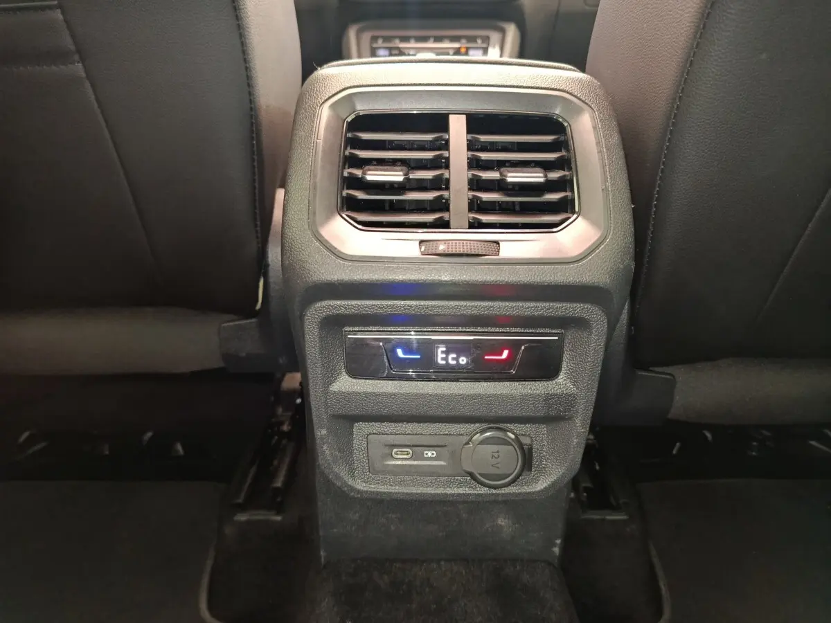 Vue rapprochée de la console arrière noire du Volkswagen Tiguan 2022 avec commandes climatisation et prises USB et 12V.