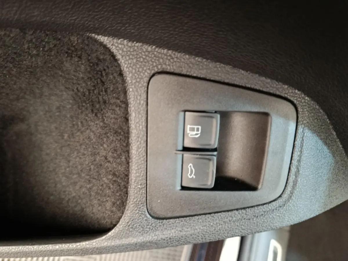 Gros plan sur les boutons d'ouverture du coffre et de la trappe à carburant dans un Volkswagen Tiguan noir 2022.