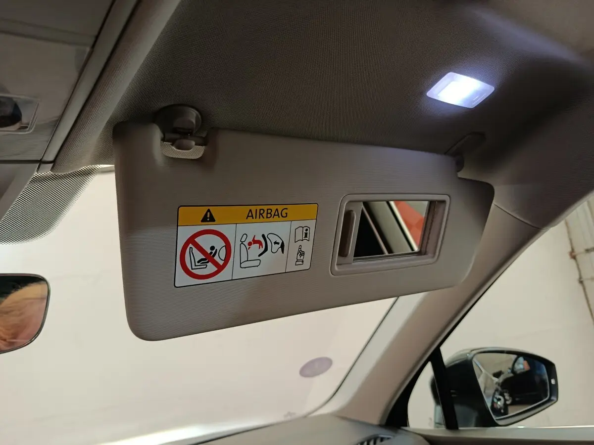 Détail intérieur du pare-soleil côté conducteur avec miroir et avertissement airbag dans un Volkswagen Tiguan noir.