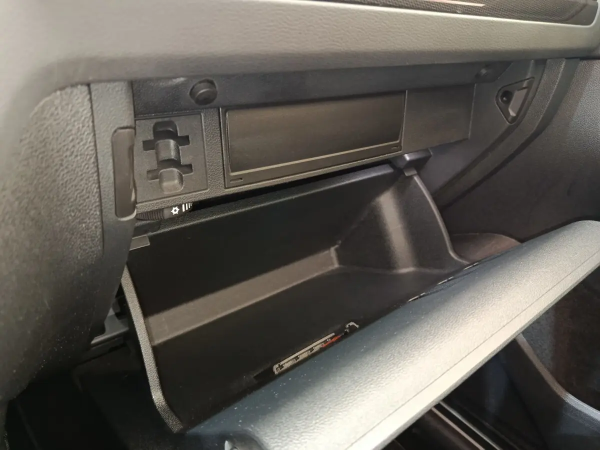 Vue intérieure sur la boîte à gants ouverte du Volkswagen Tiguan noir, version hybride rechargeable 2022.