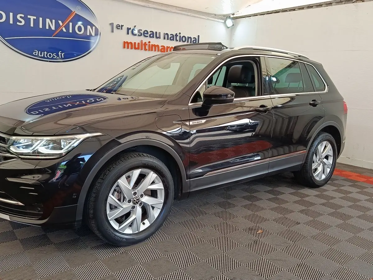 Volkswagen Tiguan 1.4 eHybrid noir en vue 3/4 avant droit, avec jantes alliage et badge hybride visible sur aile avant.