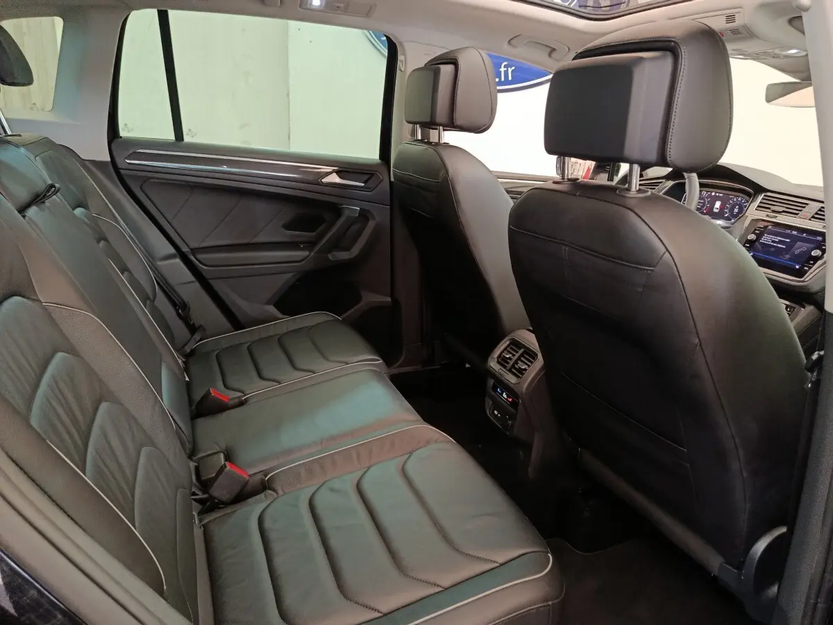 Vue intérieure côté droit montrant la banquette arrière en cuir noir et les sièges avant du Volkswagen Tiguan 1.4 eHybrid 2022.