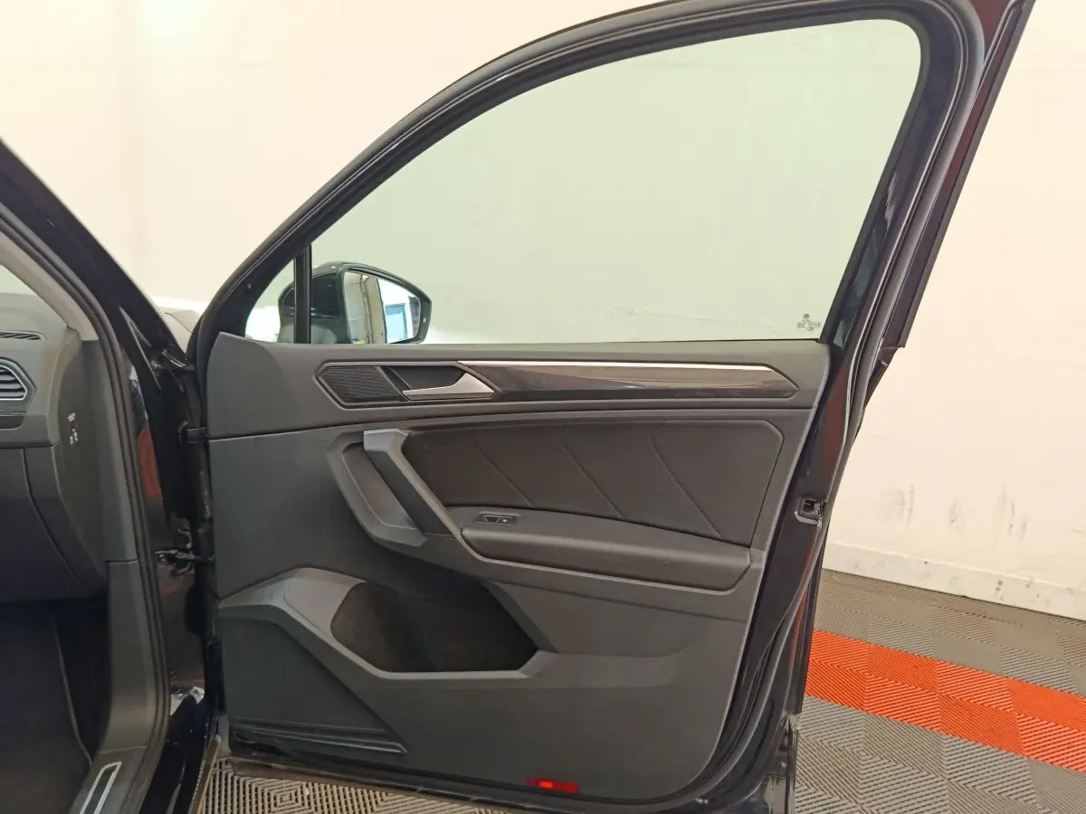 Porte avant gauche ouverte d’un Volkswagen Tiguan noir, intérieur avec garniture noire et insert décoratif gris.