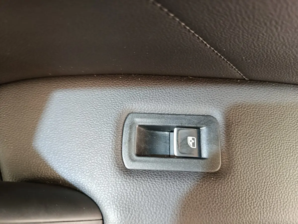 Bouton de commande de lève-vitre arrière droit sur panneau intérieur noir d'un Volkswagen Tiguan 2022.