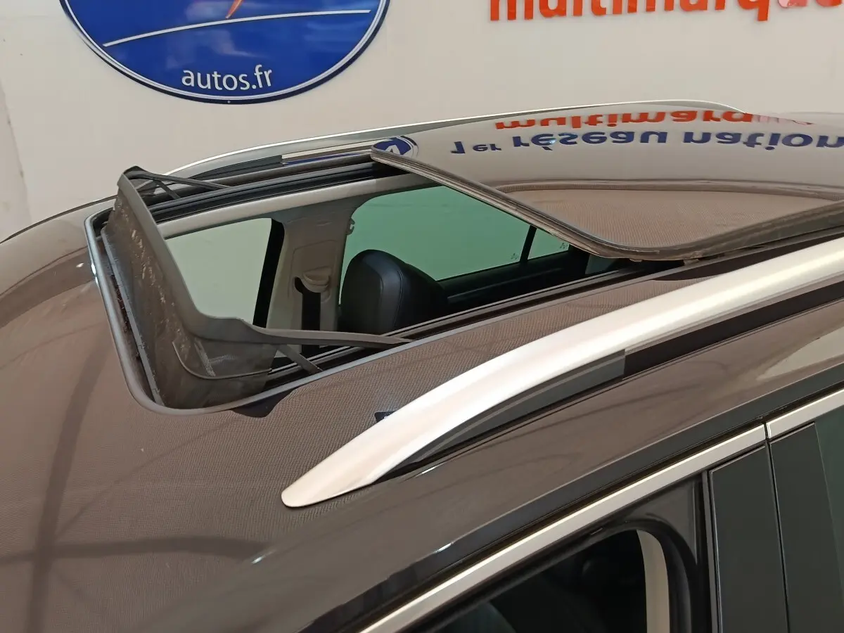 Vue rapprochée du toit ouvrant panoramique ouvert sur un Volkswagen Tiguan noir, avec rails de toit chromés visibles.