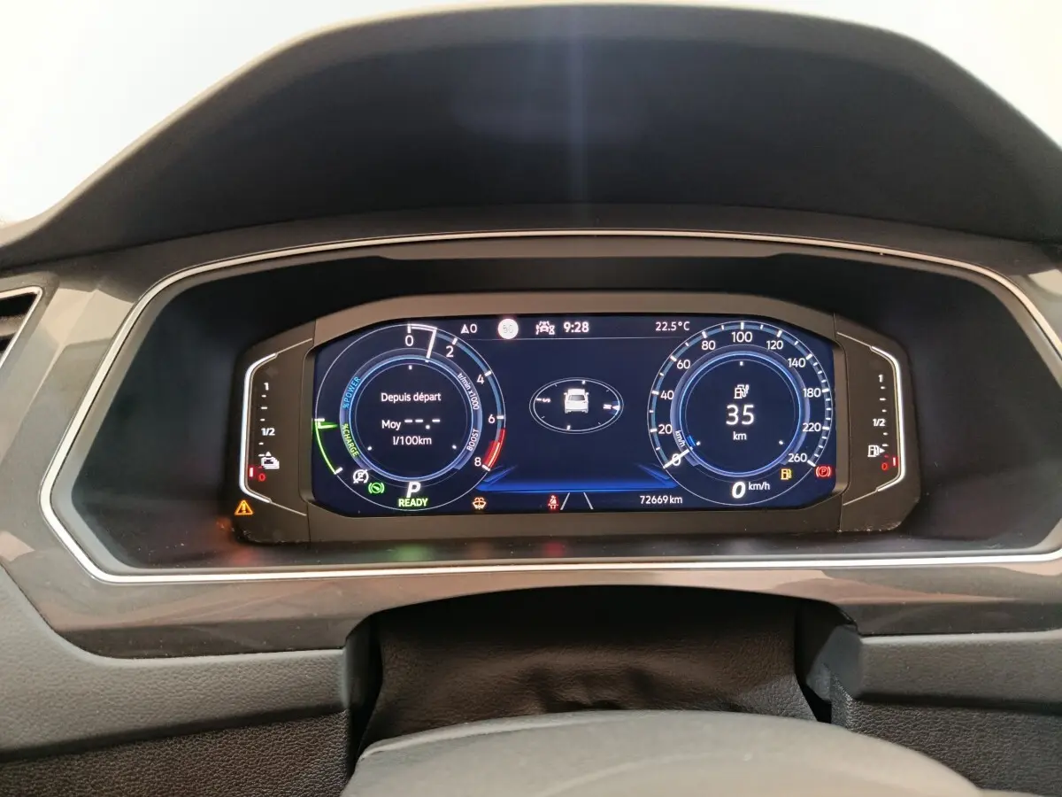Tableau de bord numérique du Volkswagen Tiguan 1.4 eHybrid noir, affichage vitesse, autonomie et consommation.