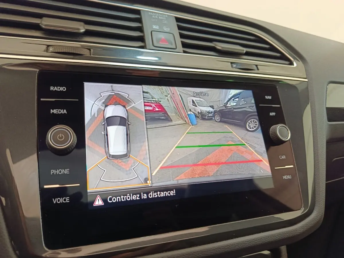 Écran tactile central montrant la caméra de recul et l’aide au stationnement du Volkswagen Tiguan noir.